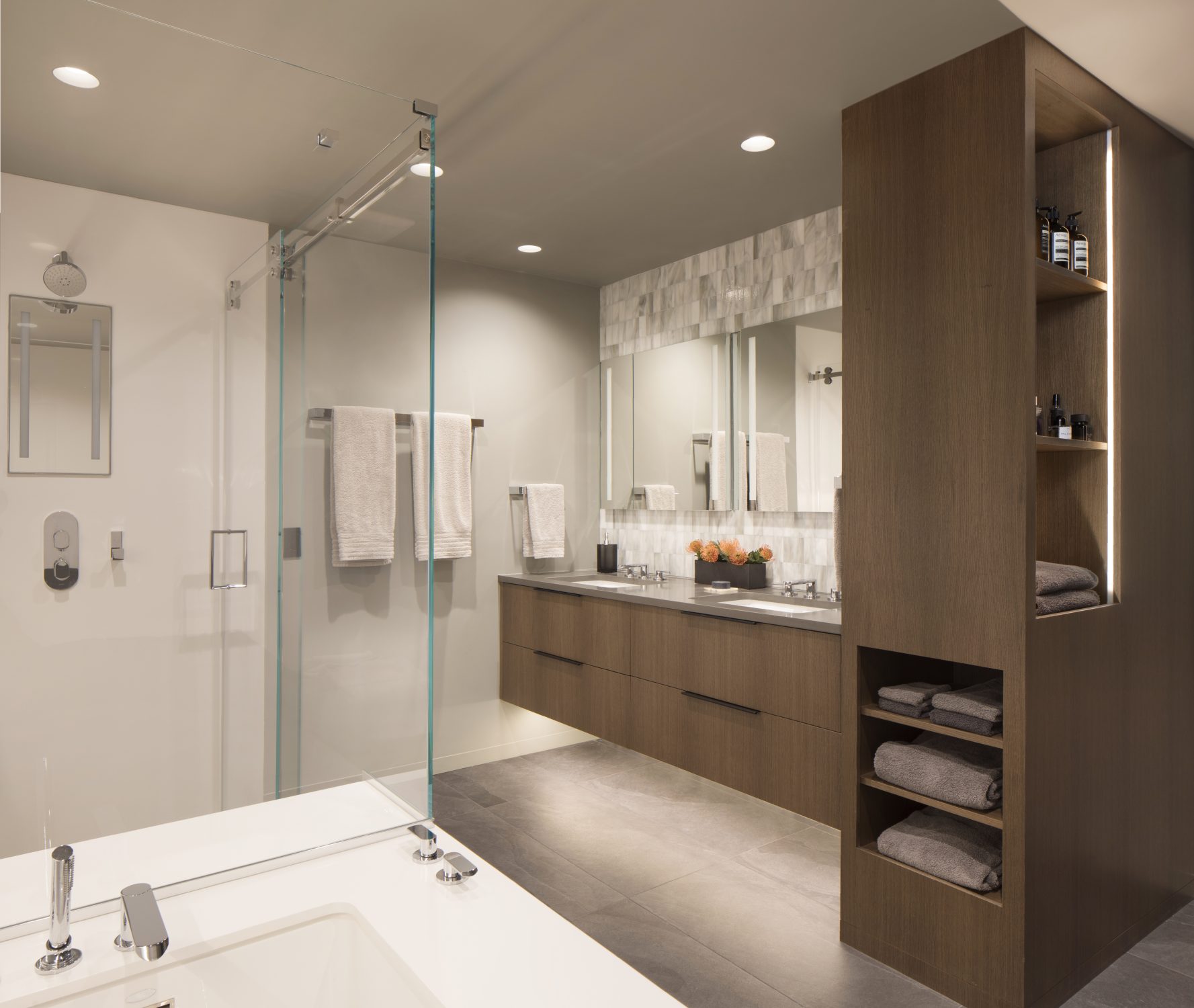 Biltmore primary bathroom with oak double vanity, glass shower, and soaking tub