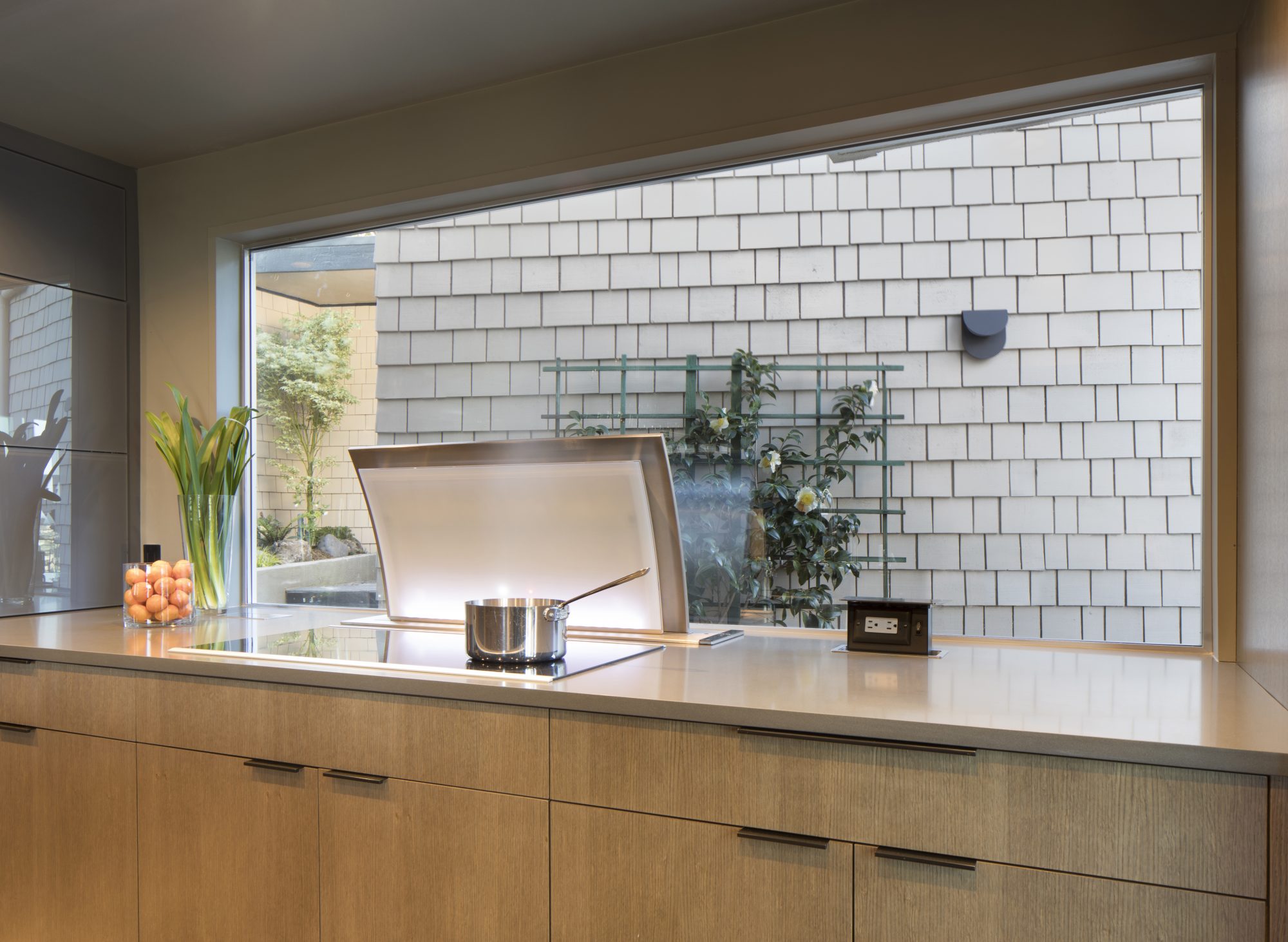 Biltmore kitchen counter with cooktop and downdraft vent beside a courtyard window