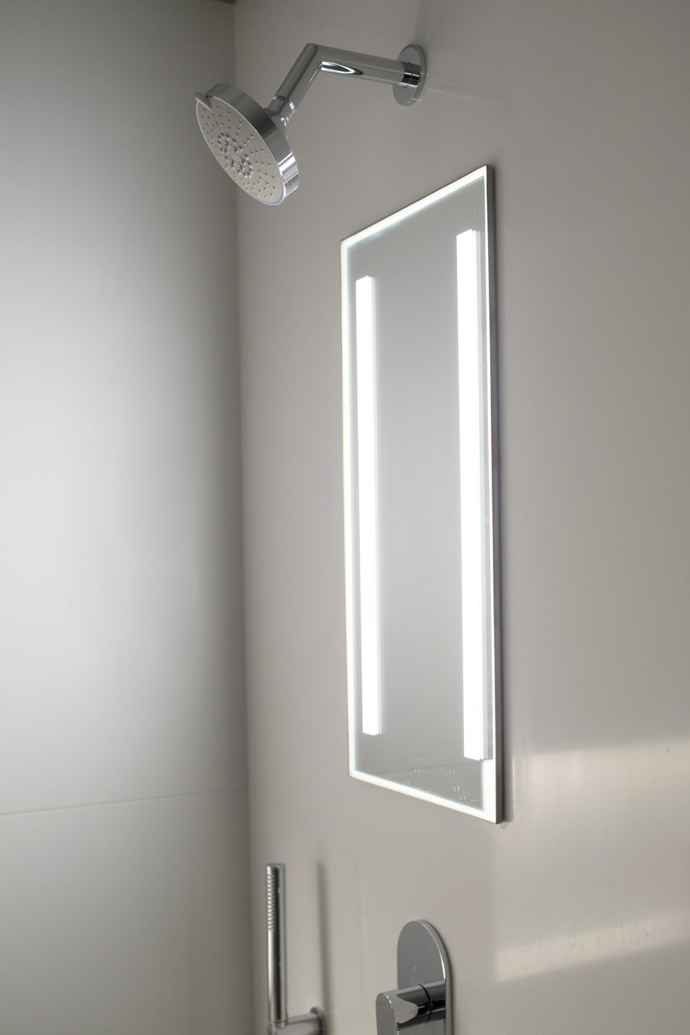 Biltmore shower with chrome fixtures and a backlit mirror