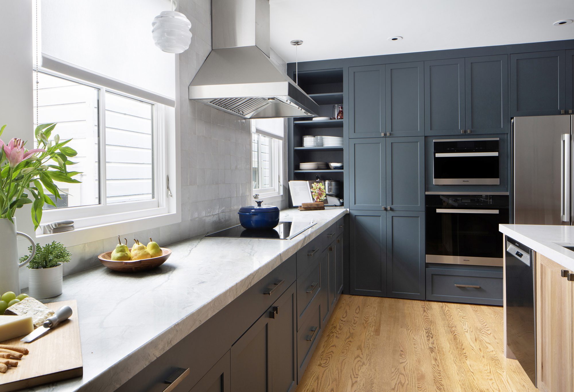 Chandler family kitchen galley view with marble counters, cooktop, and Miele wall ovens