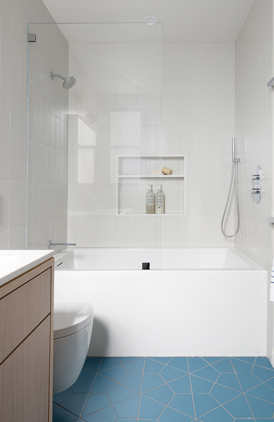 Chandler bathroom with a white-tile tub and shower and blue geometric floor tile