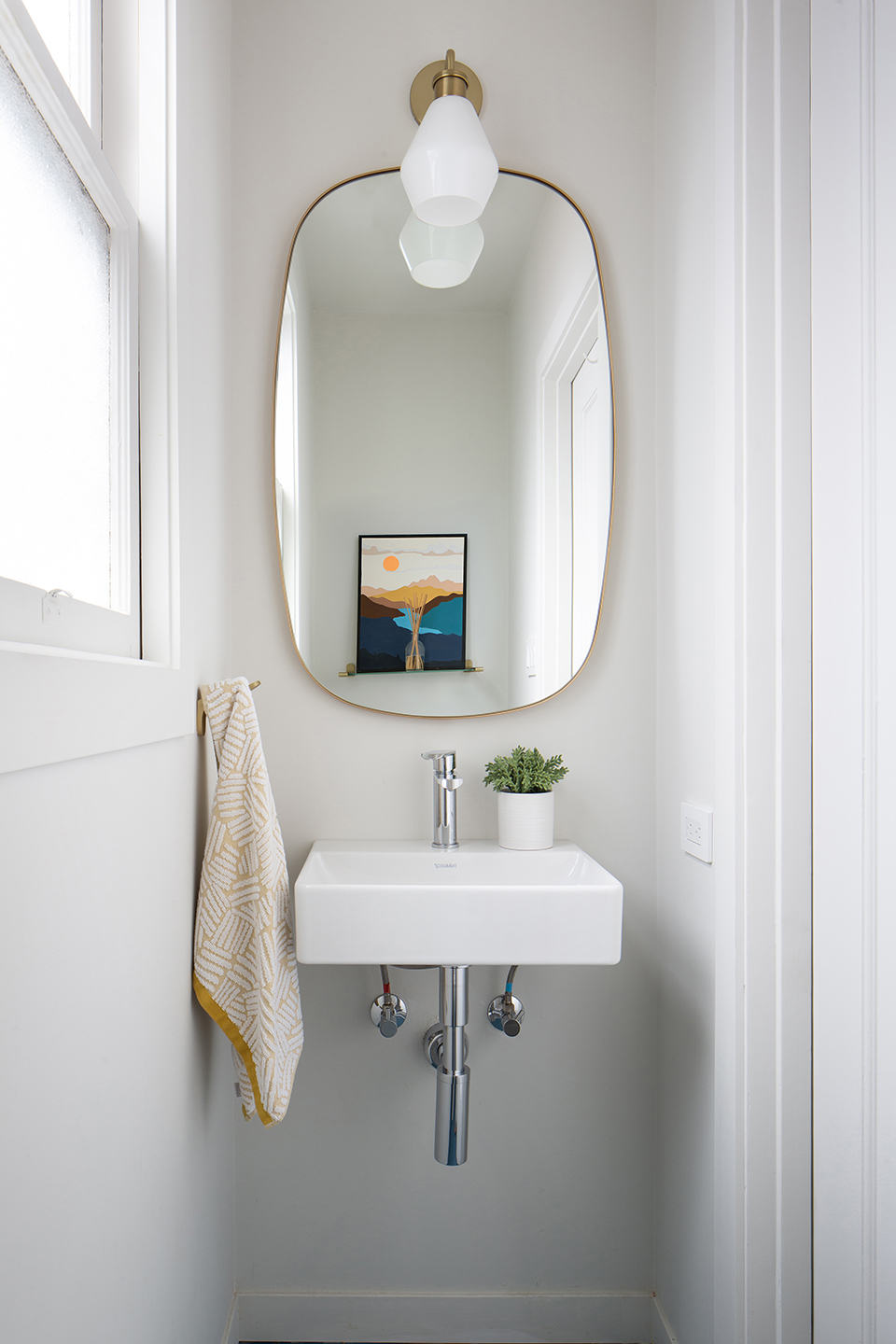 Chandler powder room with an oval brass mirror and wall-mounted sink