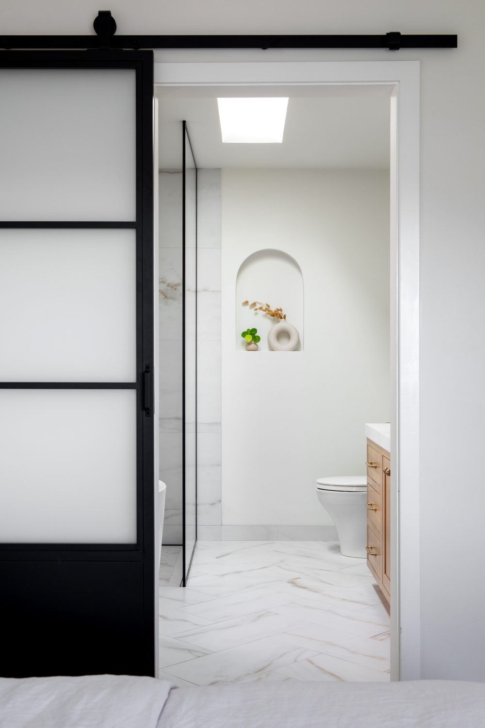 Tempe modern marble bathroom viewed through a black-frame barn door